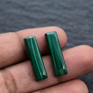 Op de afbeelding: Twee rechthoekige malachiet edelstenen met een diepgroene kleur en opvallende, natuurlijke gestreepte patronen. Deze gepolijste stenen hebben een gladde, glanzende afwerking en een verticale oriëntatie die de karakteristieke donkergroene lagen toont.