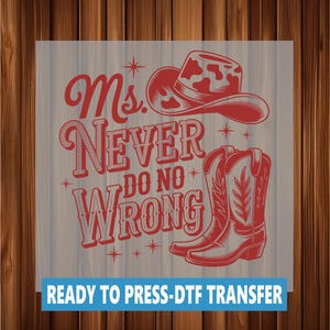 Op de afbeelding: Rood grafisch ontwerp met een cowboyhoed en laarzen met de tekst "Ms. Never Do No Wrong". Het ontwerp bevat sterren en decoratieve elementen. De tekst "READY TO PRESS-DTF TRANSFER" staat onderaan.
