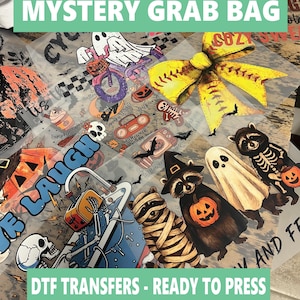 Może przedstawiać: Kolekcja transferów DTF (Direct to Film) o tematyce Halloween. Projekty obejmują ducha na rowerze, szopy pracze z dyniami, mumię i szkielet. Tekst brzmi "MYSTERY GRAB BAG" i "DTF TRANSFERS - READY TO PRESS."