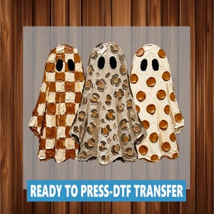 May include: A DTF transfer featuring three ghost figures with thick, textured paint strokes. The left ghost has a brown and cream checkerboard pattern, the middle has a leopard print, and the right has brown polka dots. Text reads: READY TO PRESS-DTF TRANSFER.