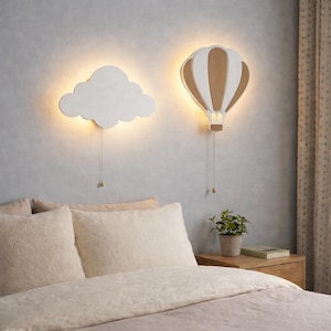 Könnte beinhalten: Ein Set aus drei Keramikbechern mit einer gesprenkelten, cremefarbenen Glasur. Jeder Becher hat ein anderes handgemaltes Design: ein blaues und grünes Blatt, eine gelbe Blume und eine rote Beere. Die Becher haben eine einfache, abgerundete Form.