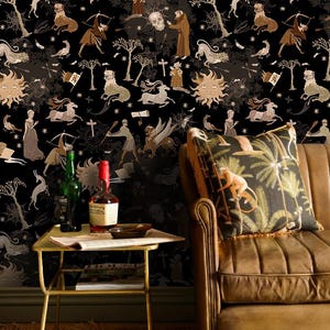 May include: Black wallpaper with a repeating pattern of mythical figures and celestial bodies. A brown leather armchair with a decorative pillow featuring a monkey and palm trees is in the foreground. A small gold table holds bottles and reading material.