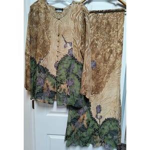 May include: A two-piece set consisting of a long-sleeved button-down blouse and a matching skirt. The fabric features a tan and brown marbled pattern with a green floral border at the hem, accented by purple flowers and dark green foliage details.
