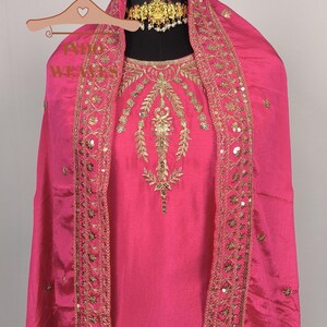 Pu&ograve; includere: Un vivace completo salwar kameez rosa. L'outfit presenta intricati ricami dorati e abbellimenti di paillettes lungo lo scollo e i bordi. Un dupatta abbinato &egrave; drappeggiato sulle spalle. Una collana girocollo dorata aggiunge un tocco di eleganza.