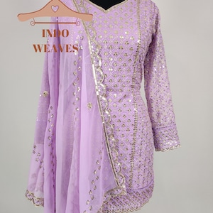 Puede incluir: Un conjunto salwar kameez lila con detalles dorados. El conjunto incluye una t&uacute;nica de manga larga, pantalones a juego y un dupatta transparente. El maniqu&iacute; muestra el bordado y el dise&ntilde;o detallados, con medidas en cent&iacute;metros.