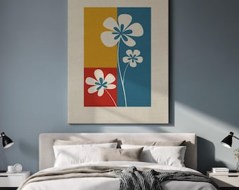 May include: A canvas wall art piece featuring a floral design. The artwork has a rectangular shape with a beige border. The design includes three white flowers with blue accents against yellow, red, and blue backgrounds.