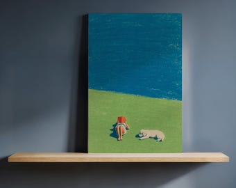 May include: A canvas print depicting a person reading a book on a green field with a blue sky background. A light-colored dog is lying down next to the person. The artwork is displayed on a wooden shelf against a dark blue wall.