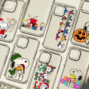 Könnte beinhalten: Transparente Handyhüllen mit Snoopy und Peanuts-Charakteren in verschiedenen Designs. Einige Hüllen zeigen Snoopy mit Weihnachtsmütze, andere mit einem Kürbis und einige mit Snoopy und Woodstock. Die Hüllen sind aus transparentem Kunststoff.