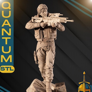 以下が含まれることがあります： ライフルを手に岩場に立つフィギュアの1/6スケール詳細像。フィギュアは戦術的な衣装を着ています。画像には「QUANTUM STL」と「SOULPS」の文字が含まれています。