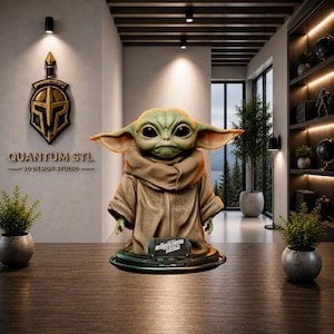 Könnte beinhalten: Detaillierte Figur von Grogu, auch bekannt als Baby Yoda, aus der Serie The Mandalorian. Die Figur ist grün mit großen schwarzen Augen und trägt eine braune Robe. Auf dem Sockel steht "Mandalorian Grogu". Der Hintergrund enthält ein Logo "Quantum STL 3D Design Studio".