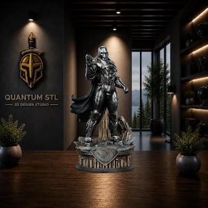 Op de afbeelding: Een metallic zilveren standbeeld van een superheld met een zwarte cape, staand op een gedetailleerde basis. Het beeld staat in een kamer met de tekst "QUANTUM STL 3D DESIGN STUDIO" op de muur. Het beeld is ongeveer 30 cm hoog.