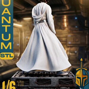 May include: A white-robed figure, a 1/6 scale model, stands on a metallic platform. The figure has a detailed hairstyle and a silver belt. The image includes the text "QUANTUM STL" and "SCULPS".