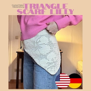 Könnte beinhalten: Ein cremefarbenes gehäkeltes Dreieckstuch mit einem komplexen Lochmuster. Das Tuch wird über einem leuchtend pinken Langarmpullover und einer blauen Jeans getragen. Der Text TRIANGLE SCARF LILLY ist oben in großen pinken Buchstaben aufgedruckt.