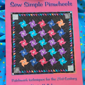 May include: A softcover book titled Sew Simple Pinwheels by Karin Hellaby with the subtitle Patchwork techniques for the 21st Century. The pink cover features a quilt illustration with a black background and colourful pinwheel patterns.