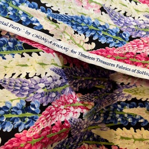 Puede incluir: Tela con estampado floral con flores rosas, azules, moradas y blancas sobre fondo negro. La tela tiene el texto "Petal Party" by CHONG-A HWANG for Timeless Treasures Fabrics of SoHo.