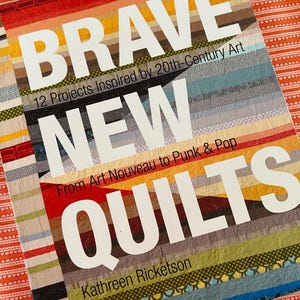 Op de afbeelding: Een boek met de titel "BRAVE NEW QUILTS" met een kleurrijke gestreepte omslag. De titel staat in grote witte letters, met de ondertitel "12 Projects Inspired by 20th-Century Art". De naam van de auteur, Kathreen Ricketson, is ook zichtbaar.