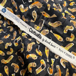 Può includere: Tessuto nero con un motivo ripetuto di uccelli stilizzati nei toni del marrone, giallo e arancione. Il tessuto include una striscia bianca con il testo "Catsville by Gareth Lucas" e "Windham Fabrics Presents."