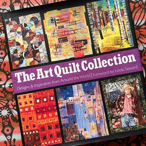Könnte beinhalten: Eine schwarze Box mit dem Titel "The Art Quilt Collection" und verschiedenen Quilt-Designs. Der Einband enthält den Text "Designs & Inspiration from Around the World" und "Foreword by Linda Seward". Der Hintergrund hat ein Blumenmuster.