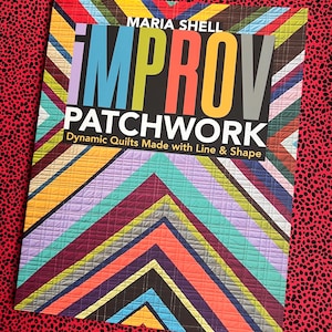 Może przedstawiać: Książka pod tytułem Improv Patchwork autorstwa Marii Shell z okładką przedstawiającą żywy, wielokolorowy geometryczny wzór w jodełkę. Tekst brzmi Improv Patchwork Dynamic Quilts Made with Line & Shape pogrubioną, kolorową czcionką.