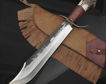 May include: A large, handcrafted hunting knife with a polished steel blade and a brown leather-wrapped handle. The handle features a decorative antler design. The knife rests in a brown leather sheath with fringe detailing.