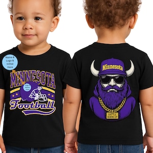 May include: Black toddler t-shirt with a Minnesota Football graphic on the front and a Viking graphic on the back. The front graphic includes the text "Minnesota Football" in purple and gold. The back graphic features a purple Viking with sunglasses.