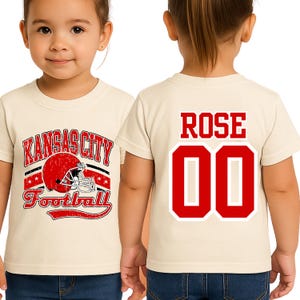 A young girl wearing a white t-shirt with a graphic design and the name "ROSE" printed on the back.