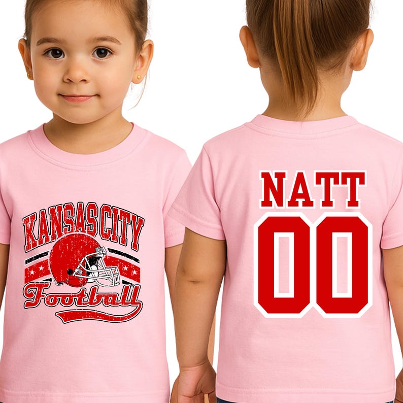 A young girl wearing a pink t-shirt with a football helmet and the text "KANSAS CITY FOOTBALL" printed on it.