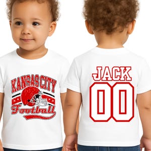 A young child wearing a white t-shirt with a graphic design and text, including the name 'Jack' and the number '00'.
