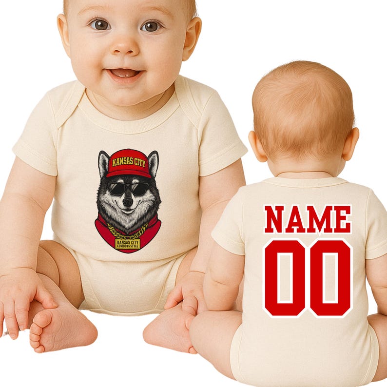 A baby wearing a white onesie with a graphic of a wolf wearing a red hat and a red bandana, sitting on the floor.