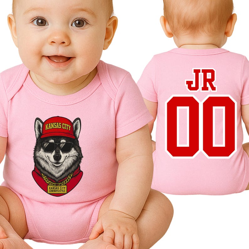 A baby wearing a pink onesie with a graphic of a wolf wearing sunglasses and a red bandana, sitting on the floor.
