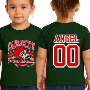 A young girl wearing a green t-shirt with a football helmet and the text "KANSAS CITY FOOTBALL" printed on it.