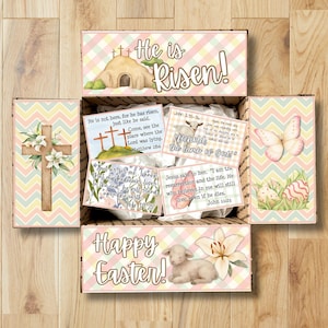 May include: An open Easter-themed gift box with pastel chevron and plaid patterns. The box contains cards with religious imagery, including a cross, lamb, and butterfly. Text includes "He is Risen!" and "Happy Easter!"