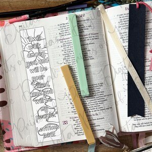 May include: A white paper bookmark with a black outline drawing of a sun and clouds featuring the text I will walk among you and will be your God and you will be my people Leviticus 26:12, alongside a dark blue bookmark with a pink tassel.