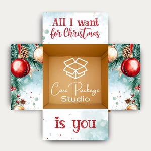May include: Open cardboard box with Christmas-themed decorations. The box's interior features the "Care Package Studio" logo. The box's flaps display the text "All I want for Christmas is you" with festive ornaments and greenery.