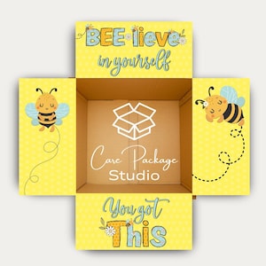 May include: An open cardboard box with a yellow interior and exterior panels. The exterior panels feature cartoon bees and the phrases "BEE-lieve in yourself" and "You got this." The interior has the text "Care Package Studio."