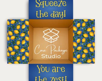 May include: An open cardboard box with a lemon-themed design. The box's interior is plain, while the exterior features blue panels with yellow text that reads "Squeeze the day!" and "You are the zest!" The box is from Care Package Studio.