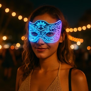 Op de afbeelding: Een vrouw draagt een oplichtend blauw en paars LED-masker met een decoratief bloemmotief. Het masker wordt verlicht tegen een vage achtergrond van warme lichten, wat wijst op een feestelijk of nachtelijk evenement. Het masker is het middelpunt.