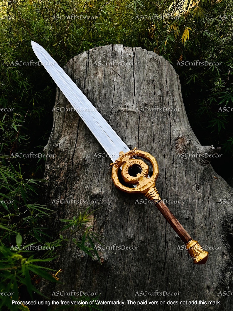 May include: A decorative sword with a silver blade and a gold-coloured handle. The handle features a brown grip and ornate gold detailing. The sword is displayed on a weathered wooden surface. The text "ASCraftsDecor" is visible.