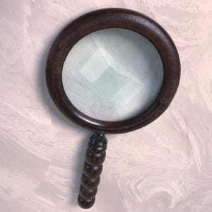 May include: A dark brown magnifying glass with a round wooden frame and a decorative handle. The glass is clear, and the handle has a series of rounded, stacked segments.