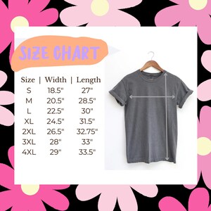 K&ouml;nnte beinhalten: Ein anthrazitfarbenes T-Shirt an einem Holzkleiderb&uuml;gel neben einer Gr&ouml;&szlig;entabelle. Die Tabelle listet die Gr&ouml;&szlig;en S bis 4XL mit den entsprechenden Breiten- und L&auml;ngenma&szlig;en in Zoll auf, die von 18,5 bis 33,5 Zoll f&uuml;r das Kleidungsst&uuml;ck reichen.