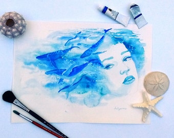 May include: Watercolor painting of a woman's face with blue whales swimming around her head. The painting is on a white background and has a blue and white color scheme.