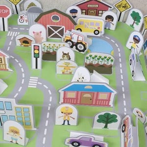 Op de afbeelding: Een kleurrijke, interactieve speelgoedstadsc&egrave;ne met wegen, gebouwen, voertuigen en figuren. Inclusief een school, boerderij, verkeerslichten en diverse borden. De sc&egrave;ne toont een schoolbus, tractor en een paarse auto.