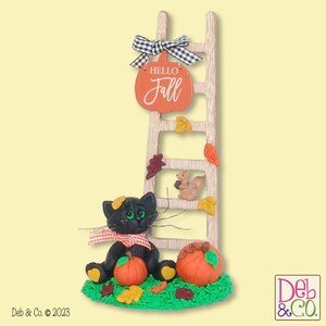 May include: A decorative fall-themed figurine featuring a wooden ladder with a pumpkin-shaped sign that reads "Hello Fall." A black cat sits at the base with pumpkins and leaves. A squirrel is on the ladder. The sign has a black and white checkered bow.