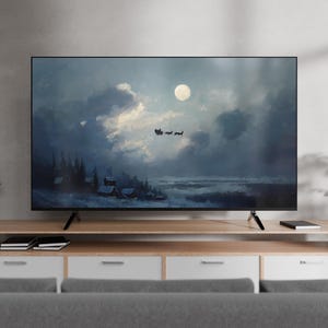 Peut inclure: Un grand écran plat affiche une peinture de paysage hivernal avec une pleine lune, des nuages et une silhouette de traîneau. La télévision est posée sur un meuble en bois clair avec des tiroirs blancs. Des plantes en pot encadrent la télévision.