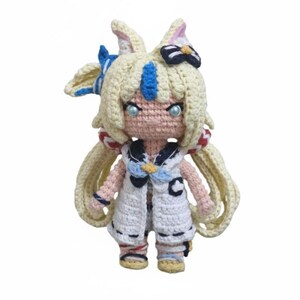 Pode incluir: Boneca de crochê feita à mão com uma roupa com tema de marinheiro. A boneca tem cabelo loiro, olhos azuis e uma roupa branca e azul com detalhes em vermelho. A boneca tem aproximadamente 15 cm de altura.