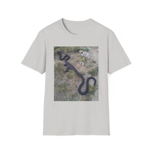 Könnte beinhalten: Hellgraues T-Shirt mit einem quadratischen Bild einer schwarzen Schlange auf braunem und grünem Hintergrund. Die Schlange befindet sich in einer gekrümmten Position. Das T-Shirt besteht aus einem weichen Material.
