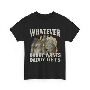 May include: Black t-shirt with the text "WHATEVER DADDY WANTS DADDY GETS" in white. The graphic features two anthropomorphic wolf-like creatures, one wearing a cowboy hat, with a full moon and flames in the background.
