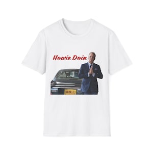 Peut inclure: T-shirt blanc avec un graphisme d'un homme en costume, les mains jointes, une voiture ancienne et le texte "Howie Dooin". La plaque d'immatriculation indique "NAMAST3".