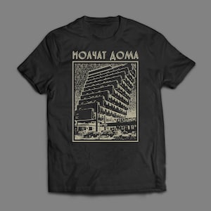 May include: Black t-shirt with a sepia-toned graphic of a high-rise building and the text "MOLCHAT DOMA". The graphic shows cars and architectural details. The shirt has a crew neck.
