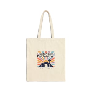 May include: A cream-coloured tote bag with a graphic design. The design features a colourful sunrise, a tomb, and a cross, with the text "Easter: Best Plot Twist Ever" and "He is risen". The bag has two handles.